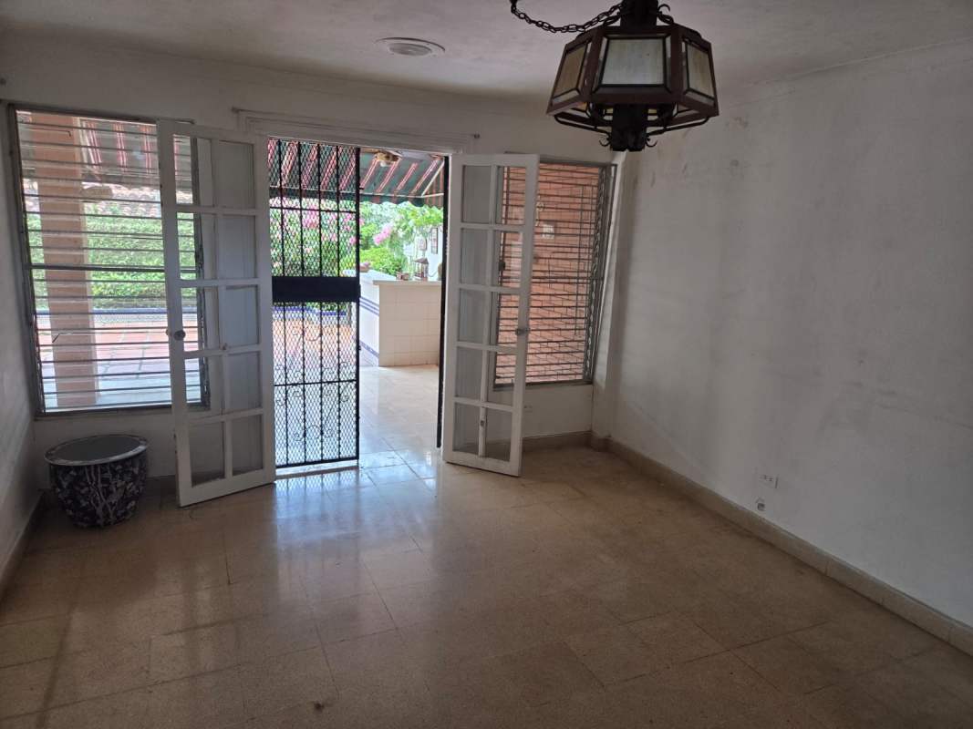 Bright living room or enclosed porch with large windows and French doors opening to patio in La Alameda Panama.