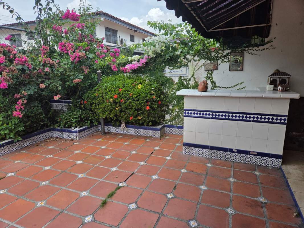 Spacious vintage kitchen with wood cabinets, vintage patterned tiles, large window with security bars in La Alameda Panama.