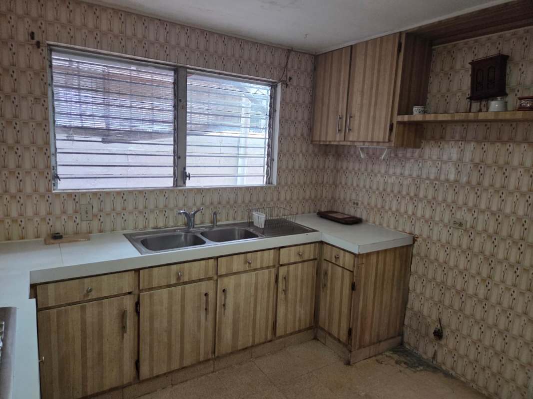 Retro kitchen with wooden cabinets, built-in oven and striped wallpaper in La Alameda neighborhood Panama City.