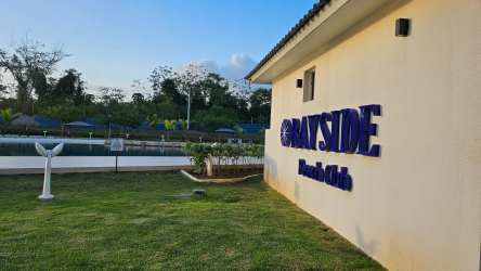 Large swimming pool at Playa Dorada beach club with tropical landscaping near ocean in Panama