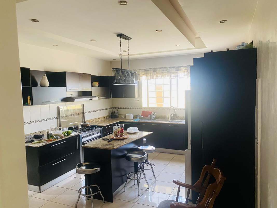 Contemporary kitchen with black cabinets, granite island, pendant lights, large window in Panama house