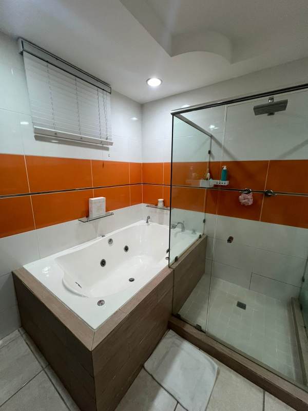 Modern bathroom with jacuzzi tub, glass shower, orange accent tiles in house for sale Brisas del Golf Panama