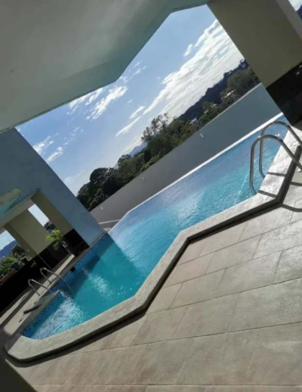 Modern living room with double-height ceiling, floor-to-ceiling windows, urban view at PH El Cangrejo Panama City