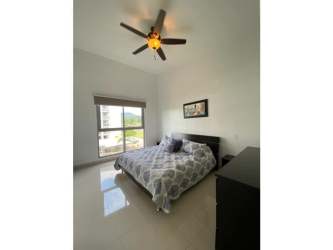 Minimalist bedroom with patterned bedding, ceiling fan, and large window in PH Soleo Panama Pacifico