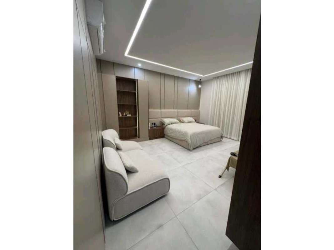 Bedroom with neutral tones, built-in shelves, queen bed, sofa and recessed lighting Santa Maria Panama luxury rental