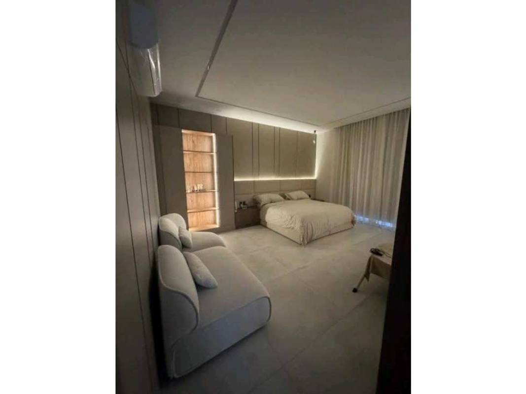 Bedroom with large flat screen, vanity area, neutral decor in The Woods Santa Maria Panama
