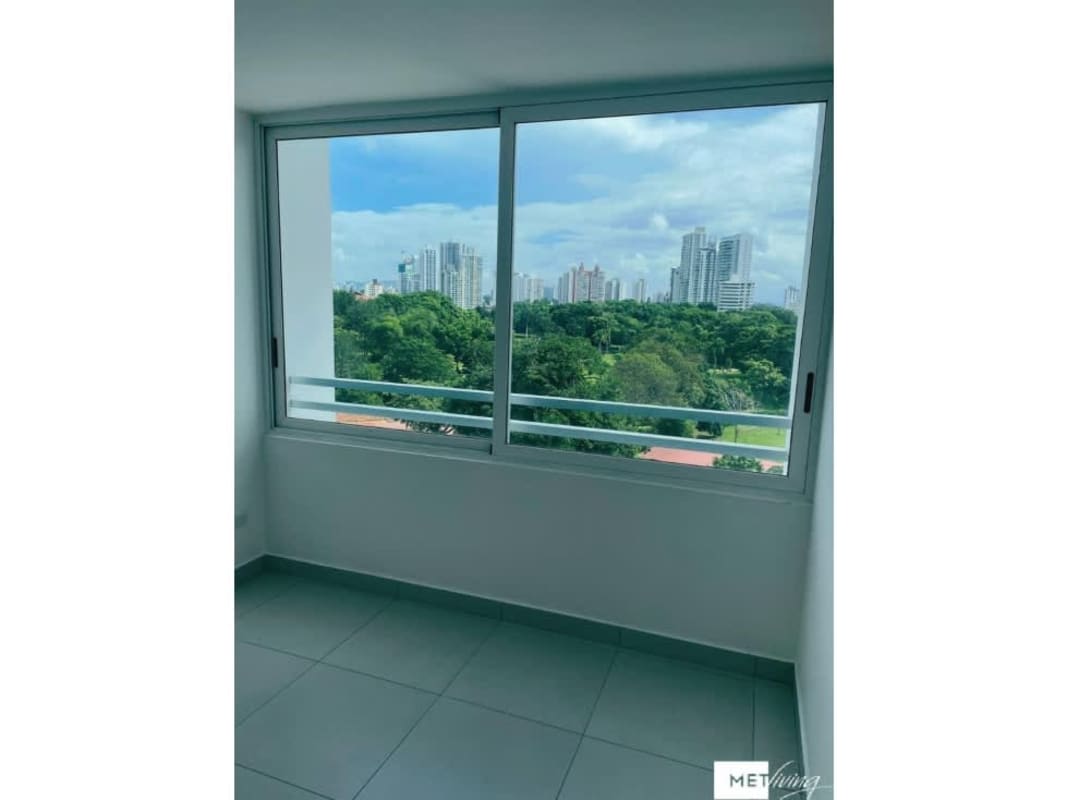 Bedroom with large window showcasing greenery of Parque Omar in PH Altos del Golf Panama City
