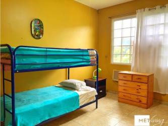 Bedroom with yellow walls, blue bunk bed, window in country home near Coronado in Rancho Los Sueños