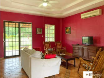 Living space with white sofa, red walls, large windows looking to garden country house near Coronado