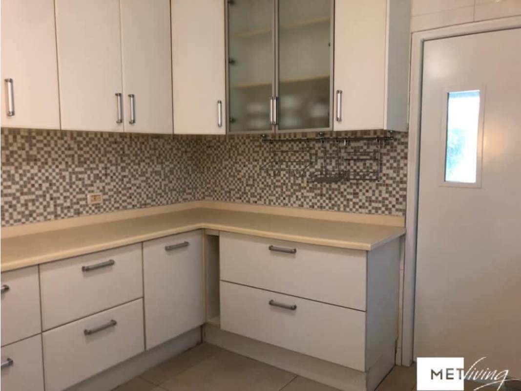 L-shaped kitchen with mosaic tile backsplash, white cabinets, built-in storage, in La Alameda Panama