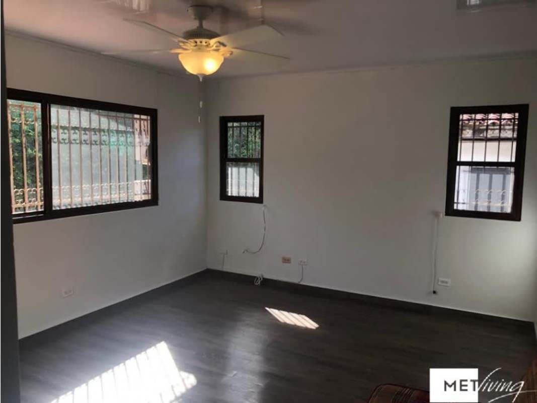 Living room with wooden floor, built-in bookshelf and cabinets, natural lighting in La Alameda Betania Panama