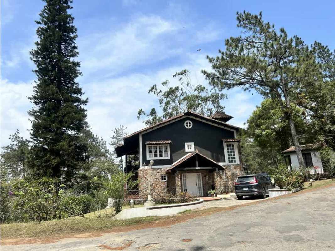 Rustic two-story country house with dark green exterior and stone accents in mountain woods Cerro Azul Panama