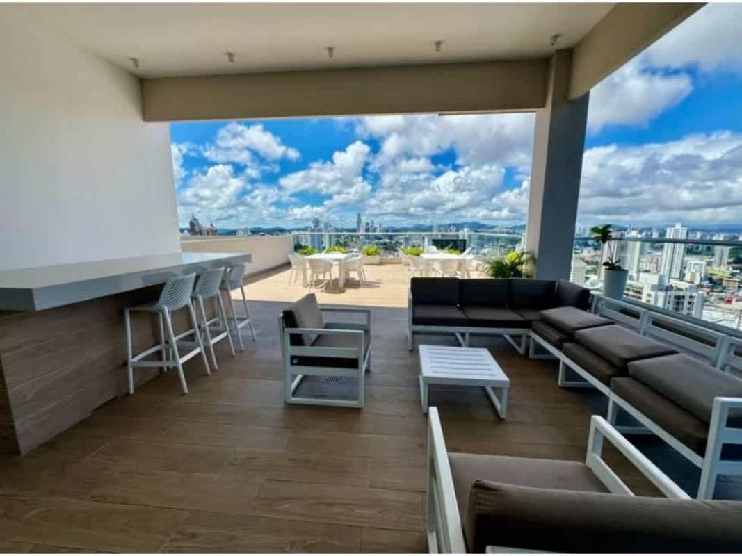 Rooftop entertainment area with bar counter, lounge seating, dining and panoramic city skyline view at PH Urbana Obarrio Panama City