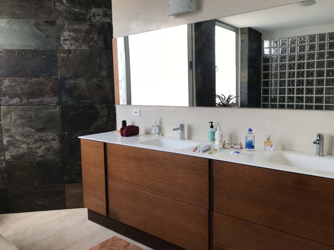 Double sink modern bathroom with stone wall and natural lighting in Junior Penthouse El Cangrejo Panama
