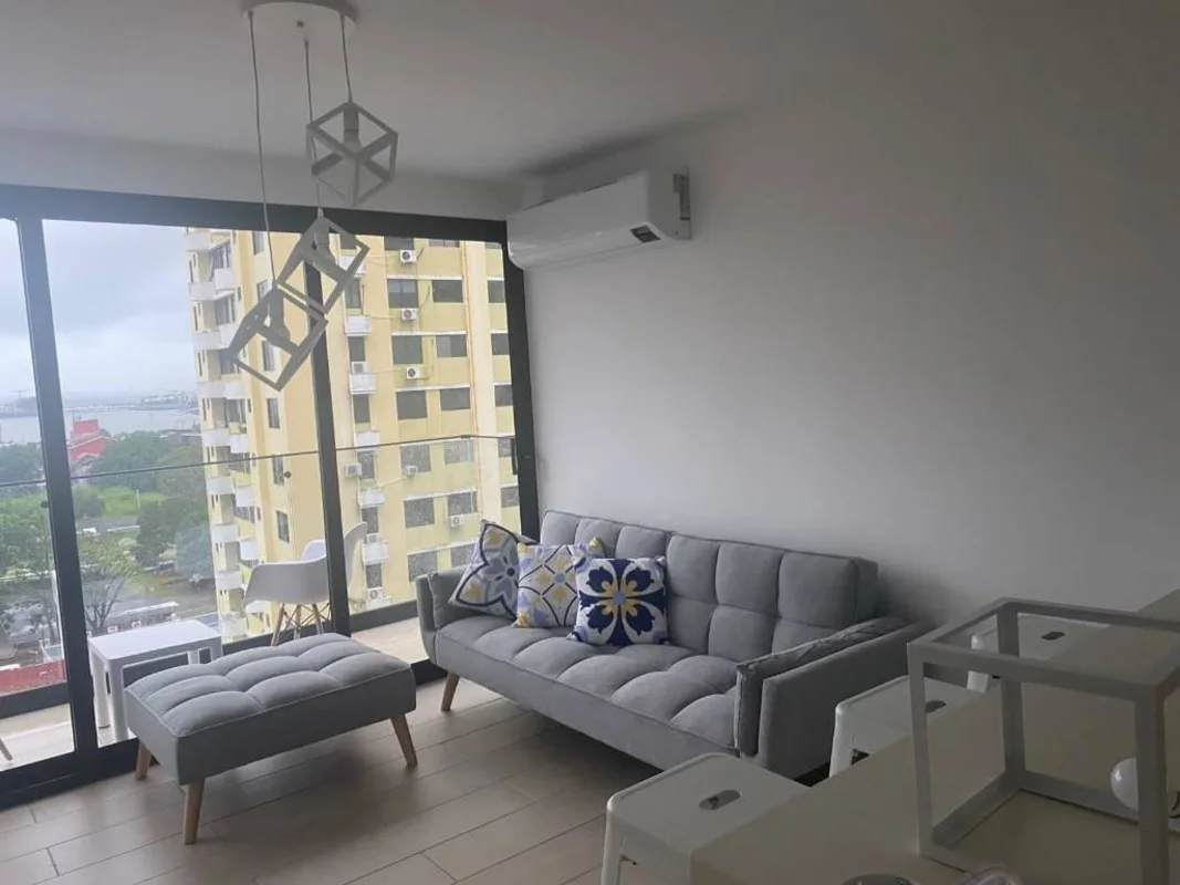 Living room with gray sofa, decorative pillows, floor-to-ceiling windows and balcony in San Francisco Bay Panama