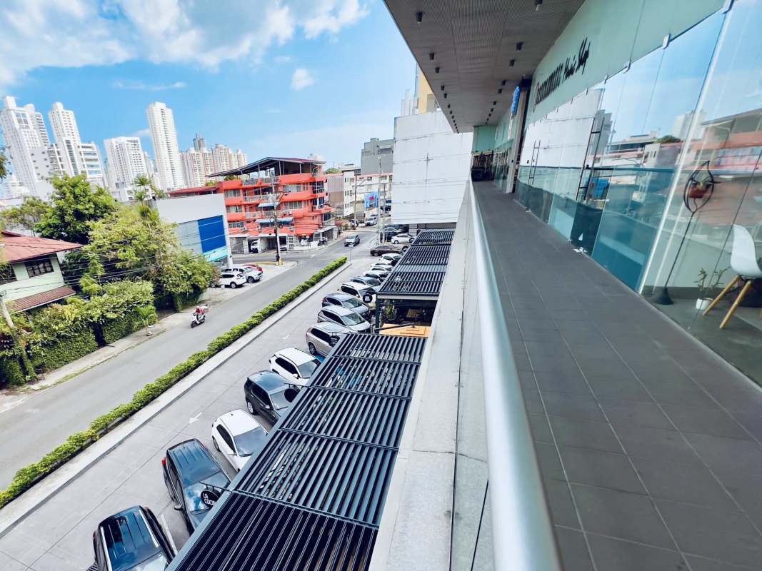 View from commercial plaza's second-floor balcony over parking and retail shops, San Francisco Panama City