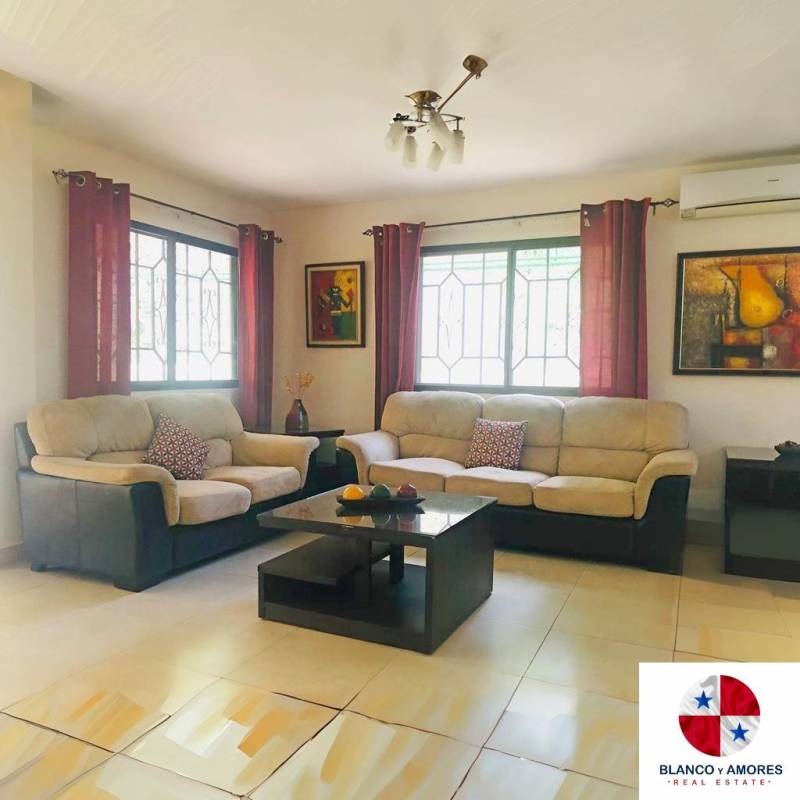Living dining area with sectional sofas, tile floors, natural light and access to terrace in Ancon Panama home