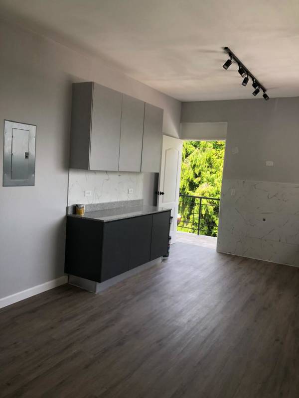 Gray kitchen cabinetry, marble backsplash, balcony door view in modern Obarrio Panama City rental apartment