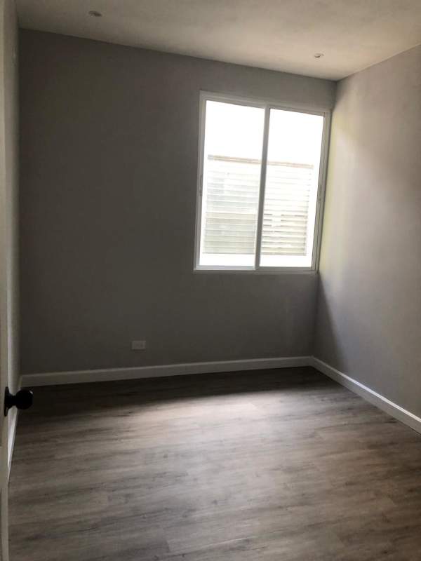 Empty bedroom with large windows, gray walls, wood floors in recently renovated Obarrio Panama apartment for rent