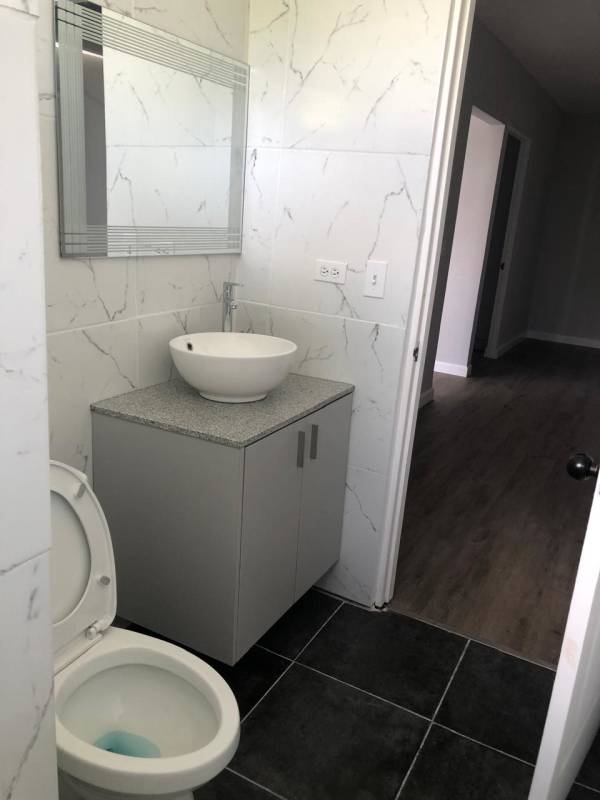 Gray vanity, vessel sink, marble patterned tile bathroom in remodeled apartment in Obarrio Panama City