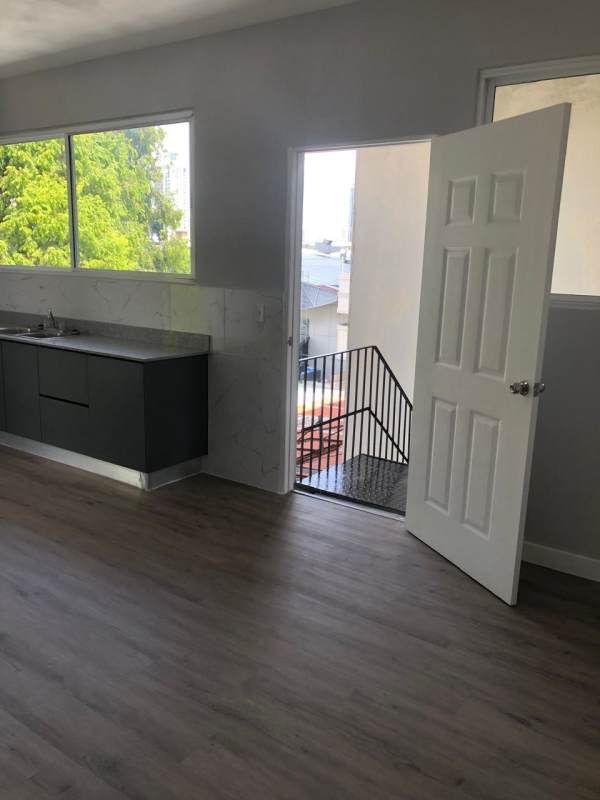 Minimalist modern kitchen with marble backsplash, floating cabinets, balcony access in Panama City apartment rental