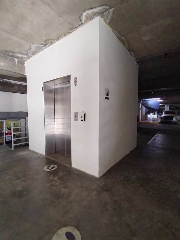Elevator located in underground parking garage with markings and concrete ceiling at Plaza El Cohete Panama