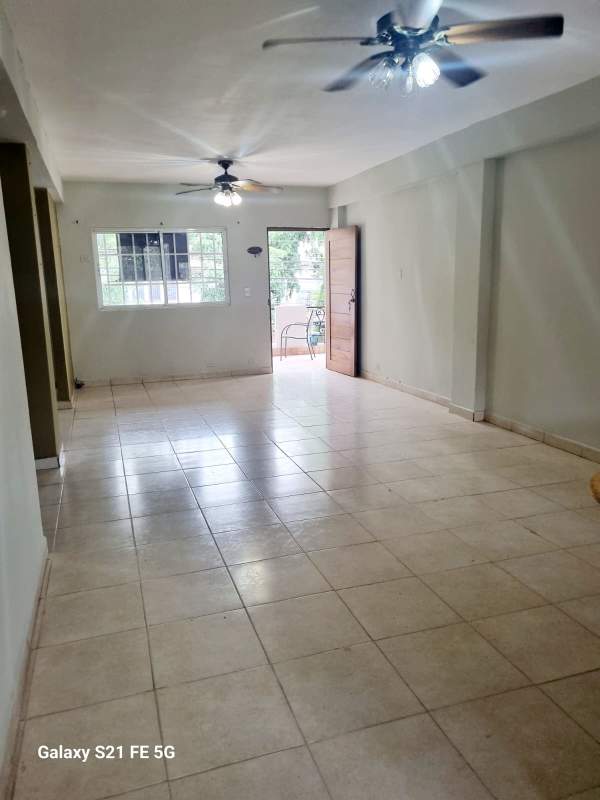 Large empty living room with tile floors, ceiling fans and access to balcony in San Francisco apartment