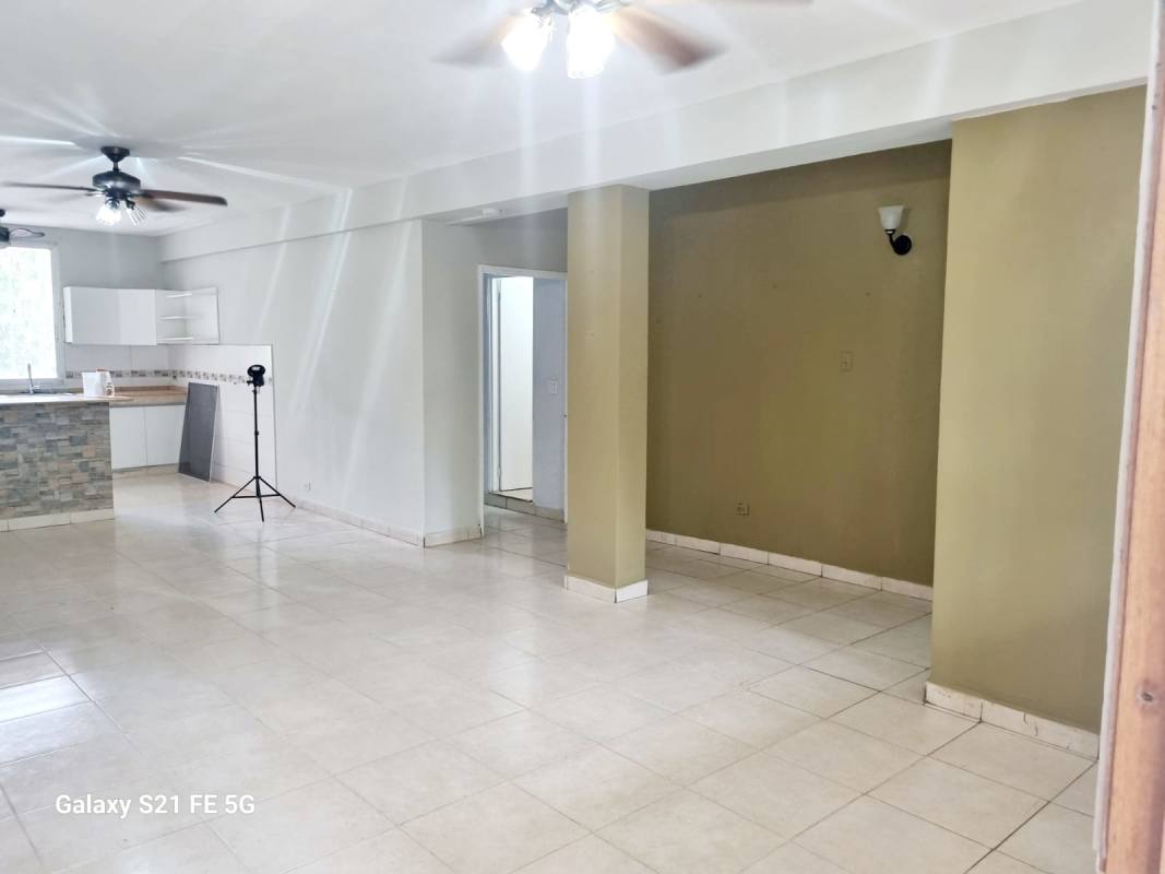 Bathroom with beige tiles, sliding shower door, ventilation window, pedestal sink in Panama apartment