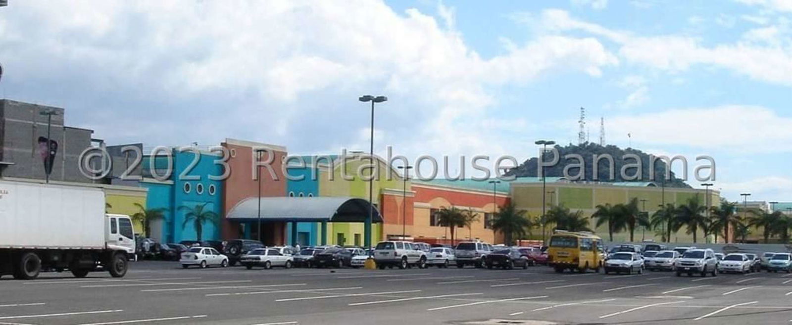 Panoramic colorful mall exterior with parking and palm trees Panama City