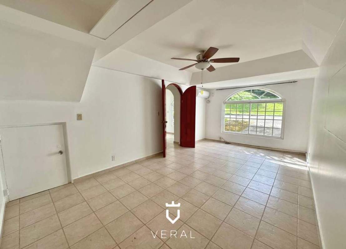 Living area with marble floors, large arched window, balcony doors at Cardenas Village Panama