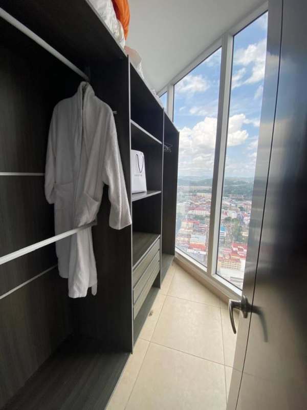Modern walk-in closet with built-ins and floor-to-ceiling window overlooking Panama skyline in PH Rivage