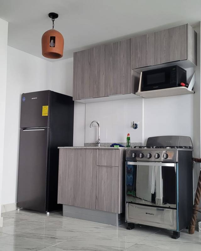 Open-plan kitchen with refrigerator, stove and tile backsplash in PH The Sands, Panama City