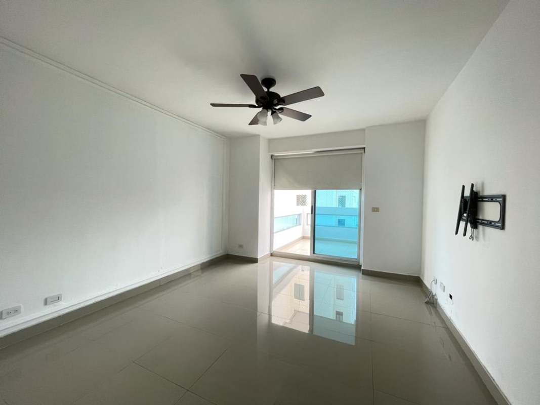 Bright living room with porcelain floors, ceiling fan, and access to ocean view balcony in Coco del Mar