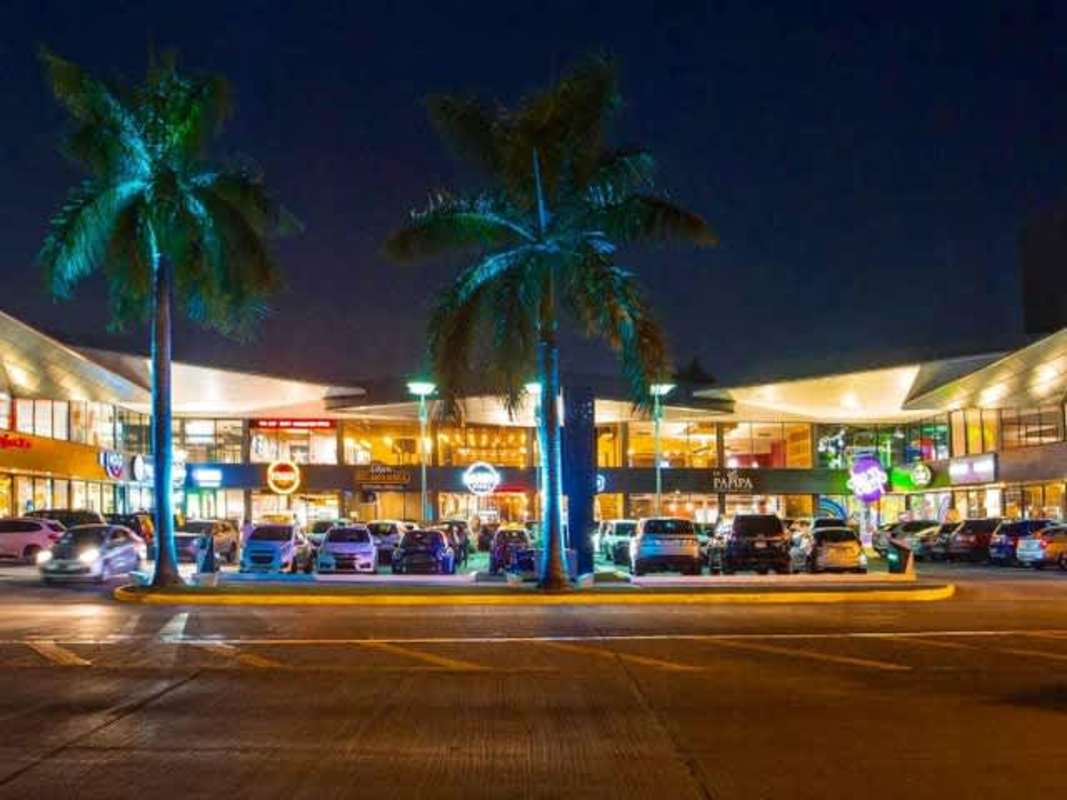 Night view of shopping center with palm trees and parking Ocean Drive Panama
