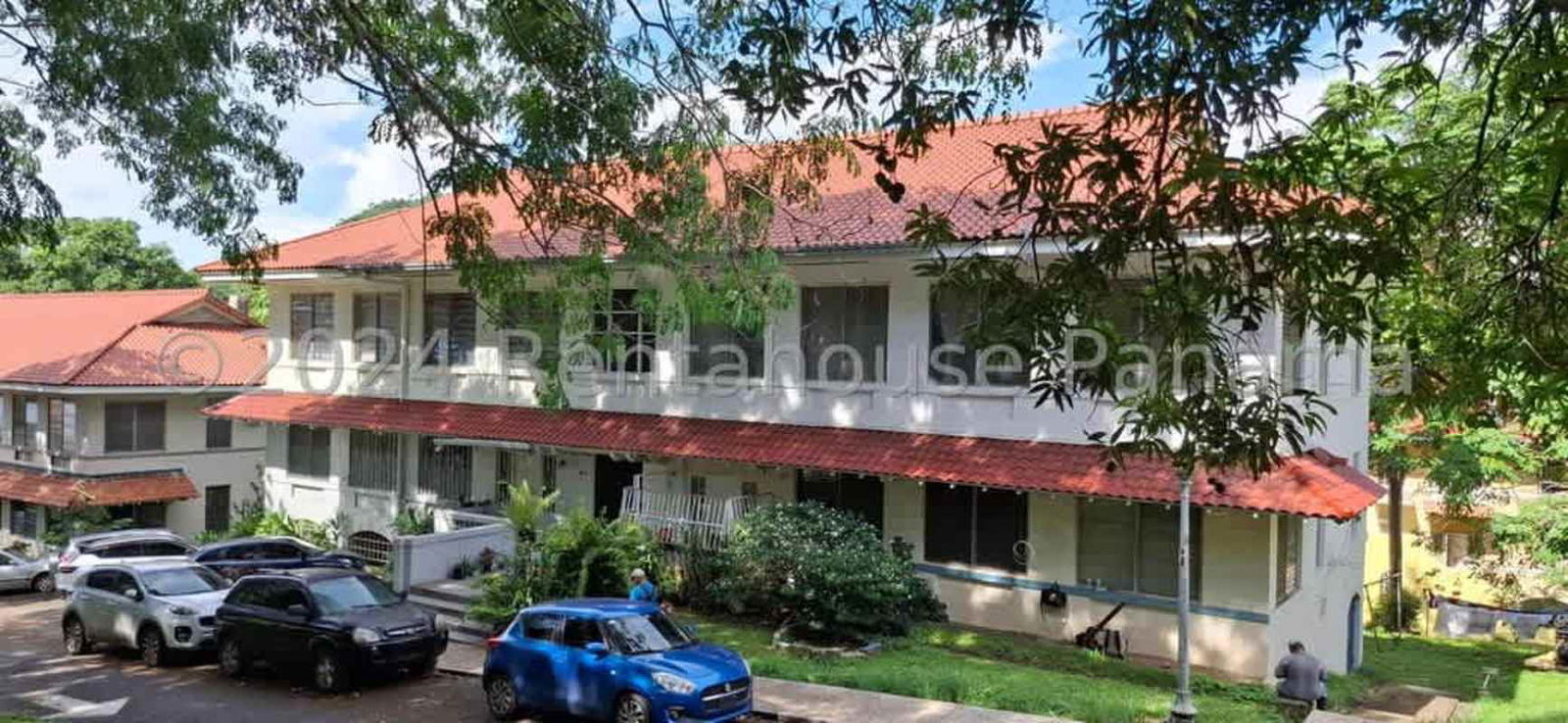 Low rise two story white building with red roof and garden in Balboa Ancon Panama City