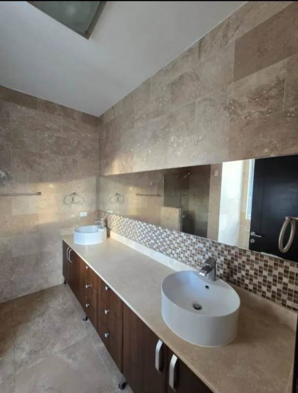 Modern bathroom with double sink vanity, glass shower and marble details in luxury rental Punta Pacífica Panama