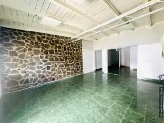 Open plan living or work area with stone wall, ceiling beams, tile floor in Doleguita commercial property