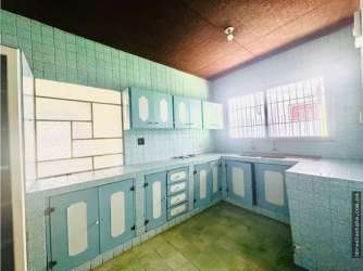 Traditional kitchen with blue tile, cabinets and barred window in commercial duplex in David Panama