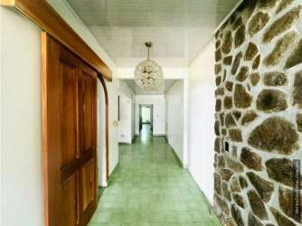 Rustic hallway featuring green tiles, stone wall, decorative light, wooden door in Doleguita commercial building