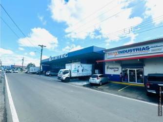 Street lined with commercial buildings, signage, delivery trucks in David Chiriquí near duplex