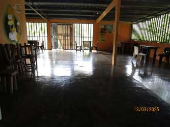 Large rustic dining hall with concrete floors, orange walls, mixed furniture in Santa Fe Veraguas