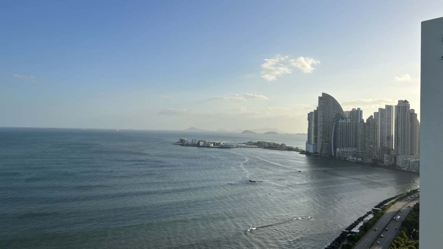 Furnished living room with sectional sofa and balcony access ocean view PH Terramar Panama City apartment for rent