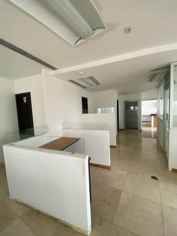 Interior office space with cubicles, glass dividers, fluorescent lighting in business district Panama City