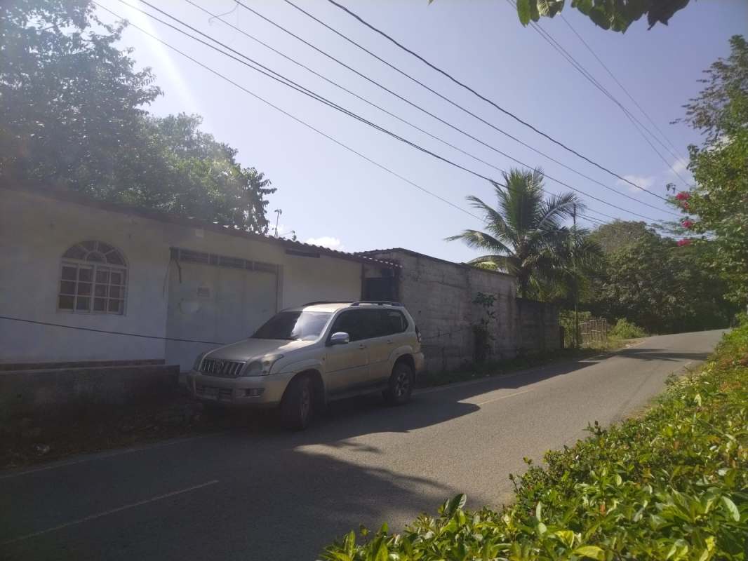Exterior view of single-story white house with porch, arched windows, brick trim Quebrada Ancha Panama