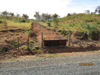 Entrance with metal gate and dirt road access to countryside lot in Santa Fe Veraguas