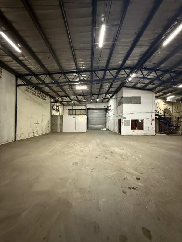 Interior warehouse with wide roll-up steel door, loading bay, and metal roof in Panama City