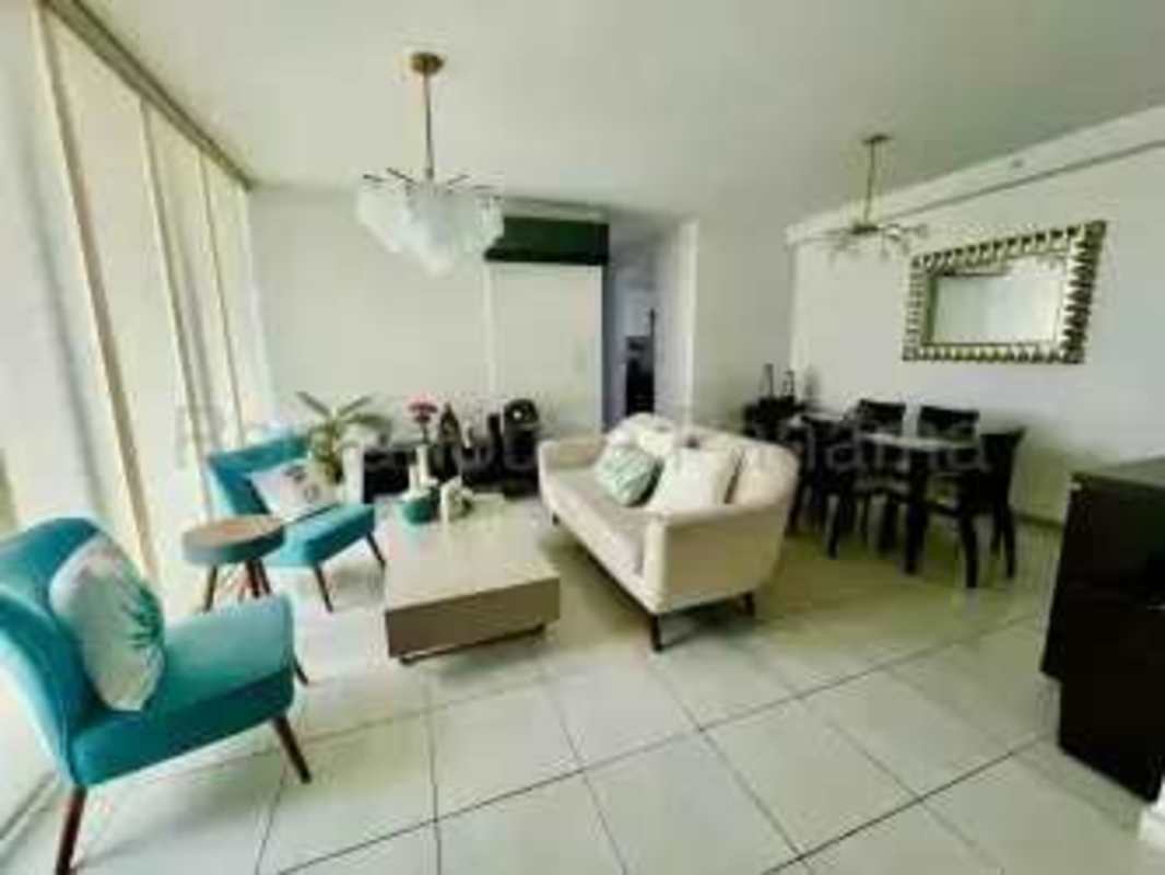 Living and dining room with large windows, turquoise chairs, beige sofa PH Trinity Panama