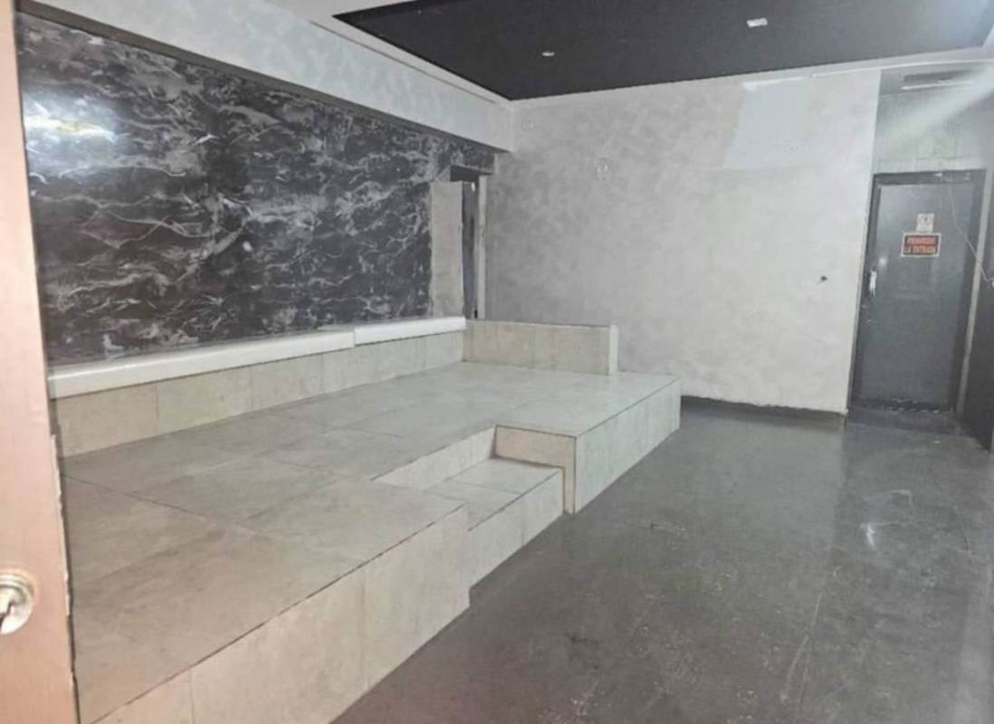 Open interior commercial space with textured wall, tile floors, metal railing Via España Panama