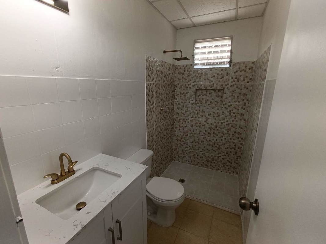 Modern bathroom shower with pebble tile wall and marble vanity Campo Limberg Panama