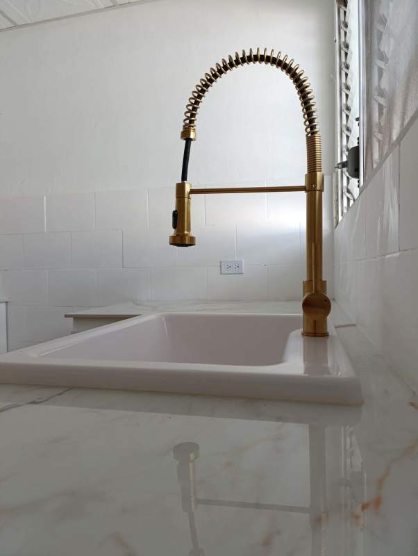 Modern kitchen with marble countertops, gold faucet and white cabinetry for rent in Don Bosco Panama